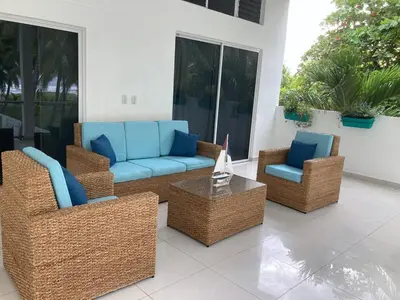 a patio with wicker chairs and a couch and a table at Oceanfront Solar Paradise-Steps to the Sea in El Zapote