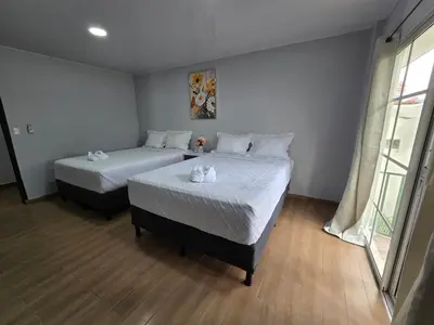 a bedroom with two beds and a window at Mi Tierra Escalón Hotel y Restaurante in San Salvador