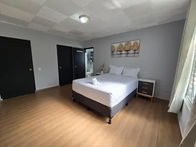 a bedroom with a large bed and a wooden floor at Mi Tierra Escalón Hotel y Restaurante in San Salvador
