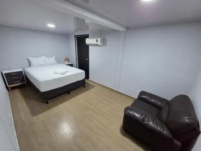 a bedroom with a bed and a leather couch at Mi Tierra Escalón Hotel y Restaurante in San Salvador
