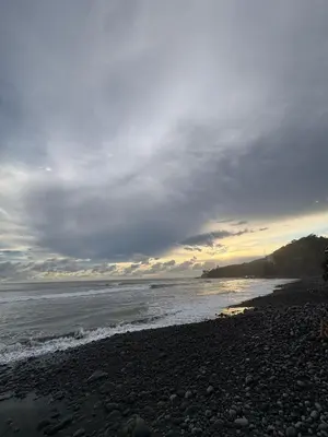 a beach with a cloudy sky and the ocean at La ceibasurf in La Libertad