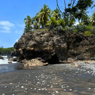 a cave on a rocky beach with palm trees at La ceibasurf in La Libertad
