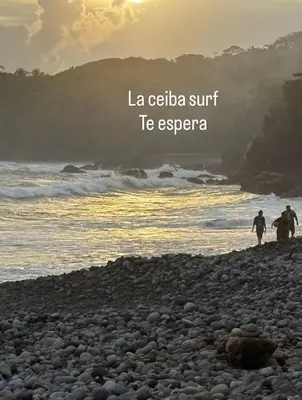 two people walking on a rocky beach near the ocean at La ceibasurf in La Libertad