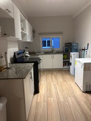 a kitchen with white cabinets and a wooden floor at Villa del Mar in La Paz