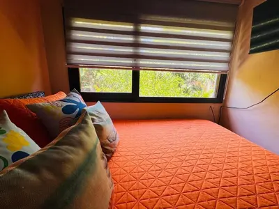 a bedroom with an orange bed with a window at Essenz Bahía in El Níspero