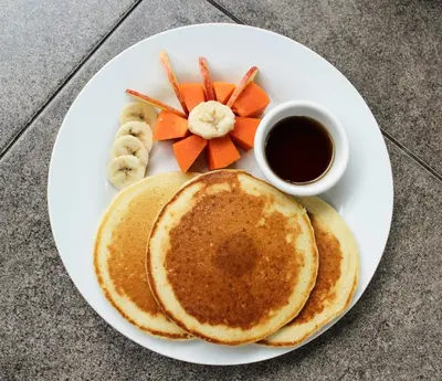 a white plate with pancakes and a cup of coffee at Hostal Casa del Sol in Suchitoto