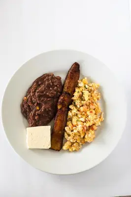 a plate of food with a hamburger and sausage and rice at Hostal Casa del Sol in Suchitoto