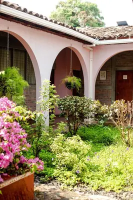 a house with a bunch of flowers in the yard at Hostal Casa del Sol in Suchitoto