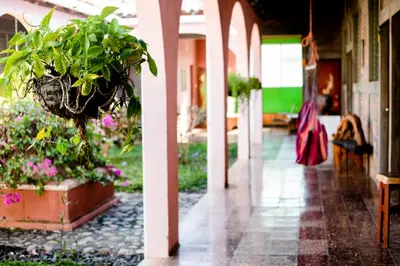 a woman walking down a hallway with plants at Hostal Casa del Sol in Suchitoto