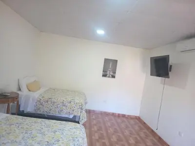 a room with two beds and a flat screen tv at Cabañas La China in El Congo