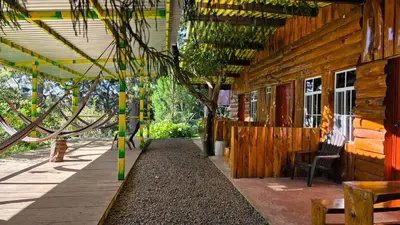 a porch of a wooden building with a table and chairs at Hostal El Pital Lecho de Flores in Nanastepeque