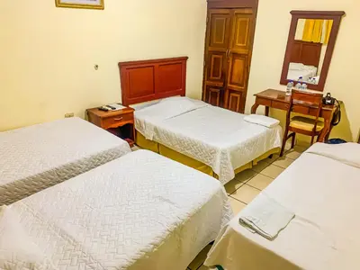 a room with three beds and a table and a mirror at Hotel Continental Plaza in San Miguel