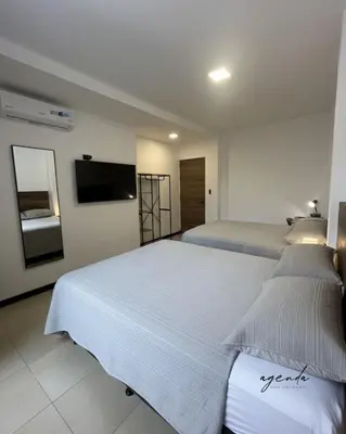 a bedroom with two beds and a flat screen tv at Agenda Hotel in San Salvador