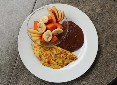 a plate of food with a bowl of oatmeal and fruit at Hostal Casa del Sol Apartamento in Suchitoto