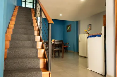 a staircase in a house with a table and a refrigerator at Hostal Casa del Sol Apartamento in Suchitoto