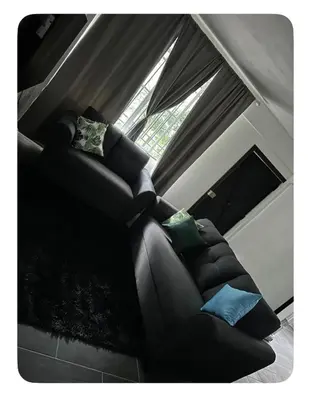 a black couch with pillows sitting in front of a window at Apartamento estadio CUSCATLAN in San Salvador