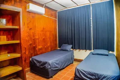 a bedroom with two beds and a window with blue curtains at Rancho Mayayi Beach house in San Miguel
