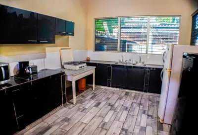 a kitchen with black cabinets and a wooden floor at Rancho Mayayi Beach house in San Miguel
