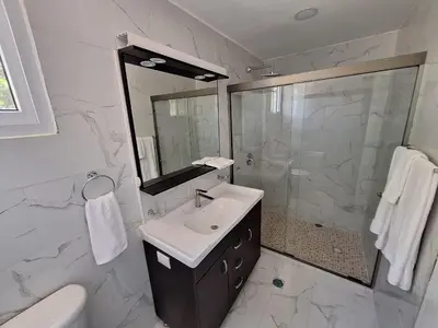 a white bathroom with a sink and a shower at The Diamond Hotel San Benito in San Salvador