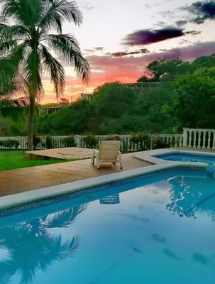 a swimming pool with a chair and a palm tree at Hotel Rancho Infinito in El Cuco