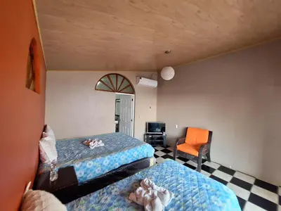 a bedroom with two beds and an orange chair at Hotel Rancho Infinito in El Cuco
