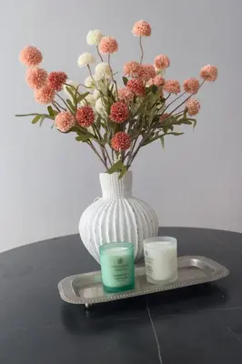 a white vase with flowers and two candles on a tray at Casa Veraneras in Santa Ana