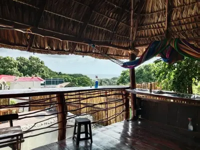 a porch with a chair and a hammock on a roof at K-Chimbón Zonte playa! Best place view! in El Zonte