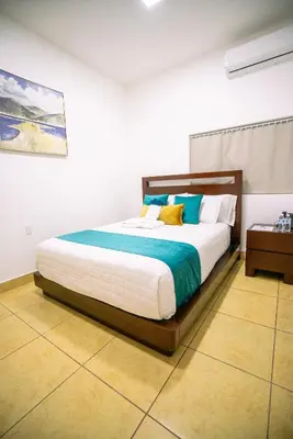 a bedroom with a bed with blue and white pillows at Suite sencilla