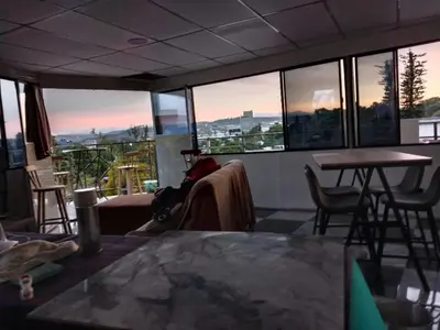 a living room with a table and chairs and windows at Habitaciones Clásica en lo mejor de SS city in San Salvador