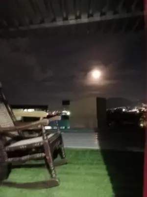 a chair sitting on the grass at night at Habitaciones Clásica en lo mejor de SS city in San Salvador