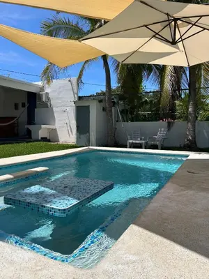a swimming pool with an umbrella and a table at BuenaMar Malibu Beach in Sonsonate