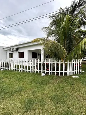 a white house with a fence and a palm tree at BuenaMar Malibu Beach in Sonsonate
