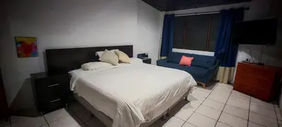 a bedroom with a bed and a blue chair at Habitación Lomas de San Francisco in San Salvador