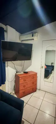 a living room with a tv and a wooden dresser at Habitación Lomas de San Francisco in San Salvador