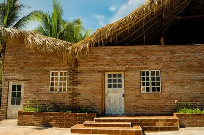 a brick building with a white door and a straw roof at Casona Tunan in Santa María Mizata