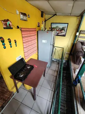 a small kitchen with a table and a refrigerator at Rooms libertad in San Salvador