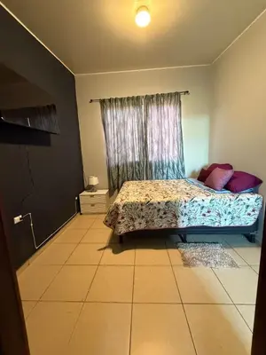 a bedroom with a bed in front of a window at Casa en residencial Metrópoli San Gabriel, Nejapa San Salvador in Nejapa