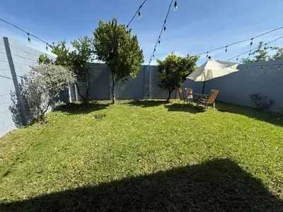 a backyard with a table and an umbrella at Casa en residencial Metrópoli San Gabriel, Nejapa San Salvador in Nejapa