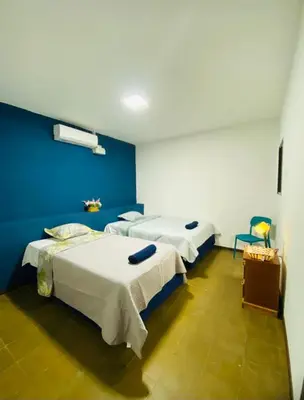 two beds in a room with a blue wall at Hostal La casa de Ross in Santa Ana