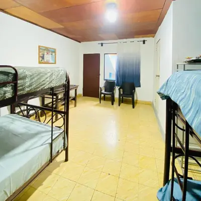 a room with two bunk beds and a desk and chairs at Hostal La casa de Ross in Santa Ana