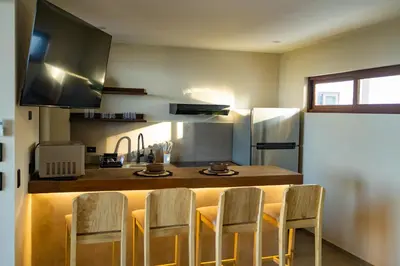 a kitchen with a bar with chairs and a counter top at 2Surf Sunzal in El Sunzal