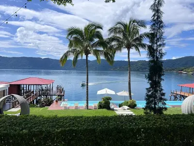 a pool with palm trees and a view of the water at Quinta Avanti Villa-Coatepeque Lake-14 guest in Santa Ana