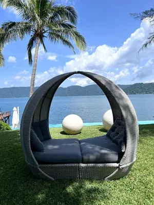 a wicker swing chair in front of a body of water at Quinta Avanti Villa-Coatepeque Lake-14 guest in Santa Ana