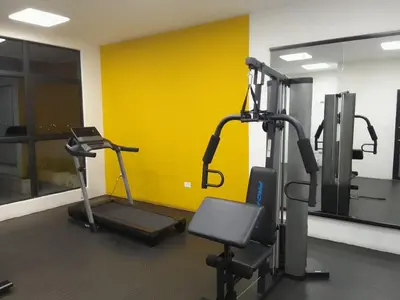 a gym with two tread machines and a yellow wall at Apartamento YOU D6 in San Salvador