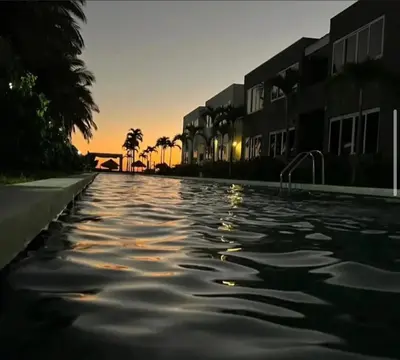 a pool of water at sunset with buildings and palm trees at Sunsets Apartment in San Luis La Herradura