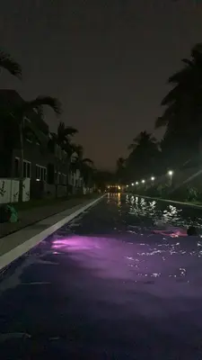 an empty swimming pool at night with purple lights at Sunsets Apartment in San Luis La Herradura