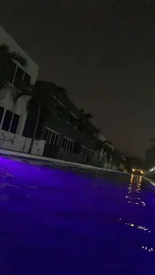 an empty pool with purple lights at night at Sunsets Apartment in San Luis La Herradura