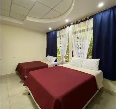 two beds in a room with blue curtains at Hotel D' Palacio Real in San Miguel
