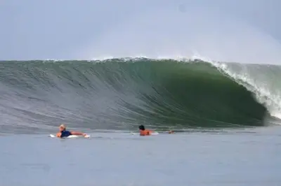 two people laying on their surfboards in the ocean at Hotel Caleta in San Miguel
