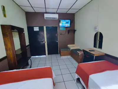 a room with two beds and a desk and a television at Hotel en Santa Ana in Santa Ana
